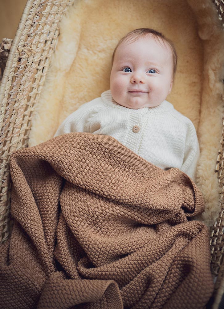 Cute baby lying in a crib and smiling while dressed in mamelo clothes